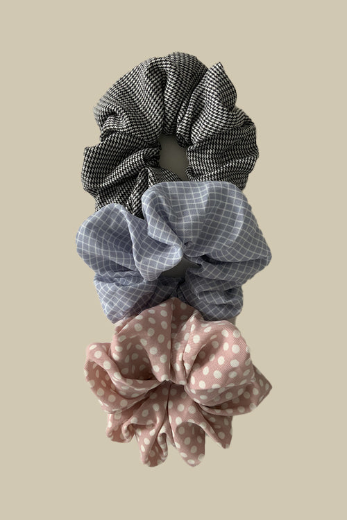 his set includes three soft fabric scrunchies in light pink, light blue, and classic black, each adorned with delightful white stripes or polka dots.