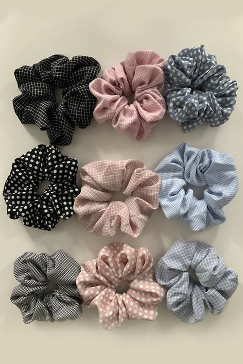 his set includes three soft fabric scrunchies in light pink, light blue, and classic black, each adorned with delightful white stripes or polka dots.