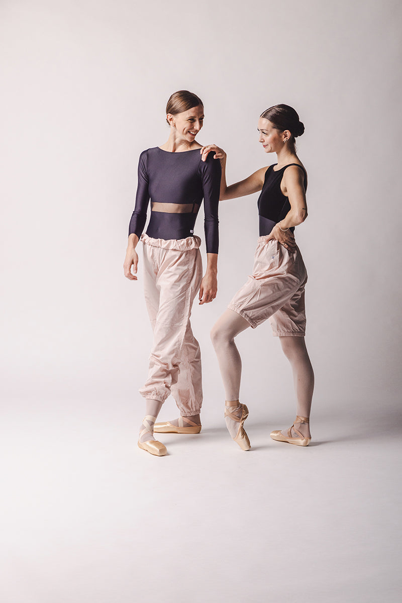 The dancers are wearing Trashbag Pants, perfect warm up pants color: light pink , By worldwide Ballet. in this picture, on the left side Shorts on the right side long trash bagpants